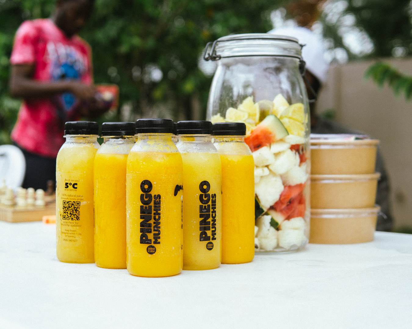 Bottles of Pinego Munchies juice with a jar of fresh fruit